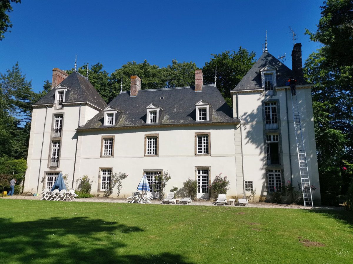 Grande demeure à toiture en ardoise, échelle posée contre la façade