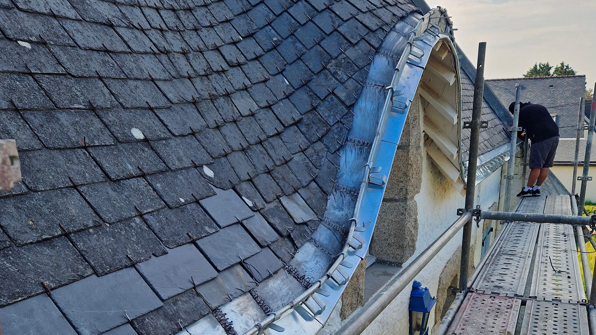 Bordure en zinc le long d'une toiture en ardoise, échafaudage en place